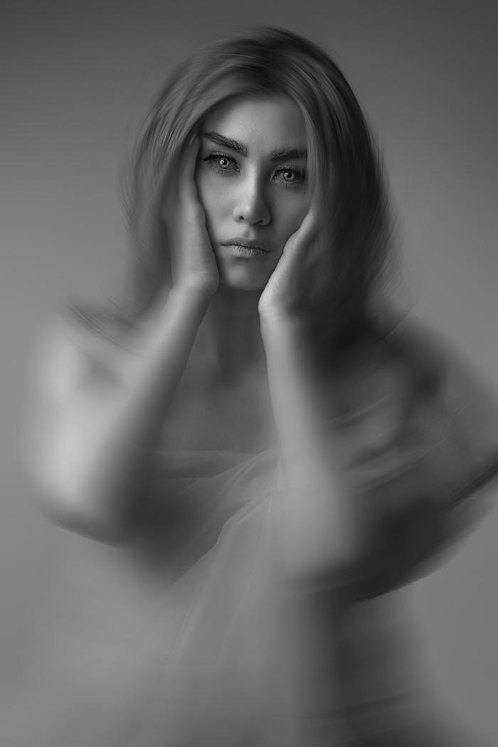 about-us-01 Artistic black and white portrait of a woman with a blurred effect, conveying a mysterious and ethereal mood.